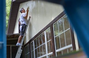 volunteer painting outside of a house