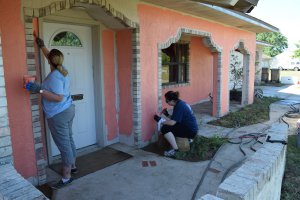 preservation and repair volunteers painting front of the house