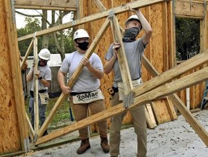 Joshua Fulwider, left, Abigail Stewart, center, and Jakobe Zick bring in a roof truss to be raised on a home being built for Habitat for Humanity Lake Sumter on Oct. 12 on Ann Street in Lady Lake. George Horsford, Daily Sun