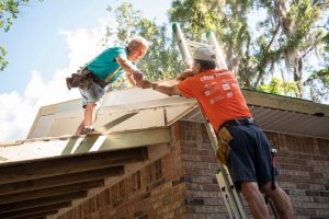 Volunteers from Habitat for Humanity work on repairing siding on the roof at the home in Leesburg. Cindy Peterson/Correspondent
