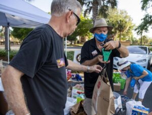 Evening Rotary Club of The Villages club member Marvin Ivy, right, of the Village of Poinciana, weighs a bag of food donations as part of a food drive by the three Rotary Clubs of The Villages. Michael Johnson, Daily Sun