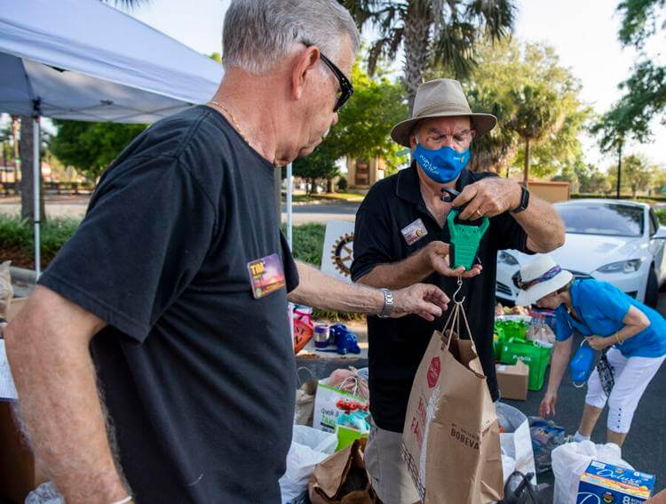 Evening Rotary Club of The Villages club member Marvin Ivy, right, of the Village of Poinciana, weighs a bag of food donations as part of a food drive by the three Rotary Clubs of The Villages.  Michael Johnson, Daily Sun