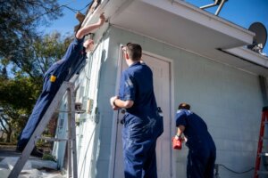 Cadets from the Massachusetts Maritime Academy paint a house in Mount Dora as part of Habitat for Humanity’s Preservation and Repair program on Thursday. [Cindy Peterson/Correspondent]