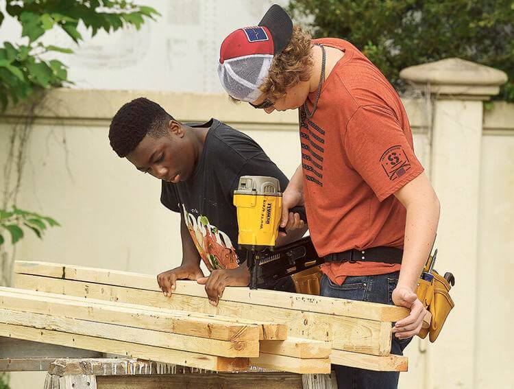 Eleventh-graders Benjamin Sylaince, left, and Cason Wiggin, of the Leesburg High School Construction Academy, use a nail gun as they work on the Habitat for Humanity home.  George Horsford, Daily Sun